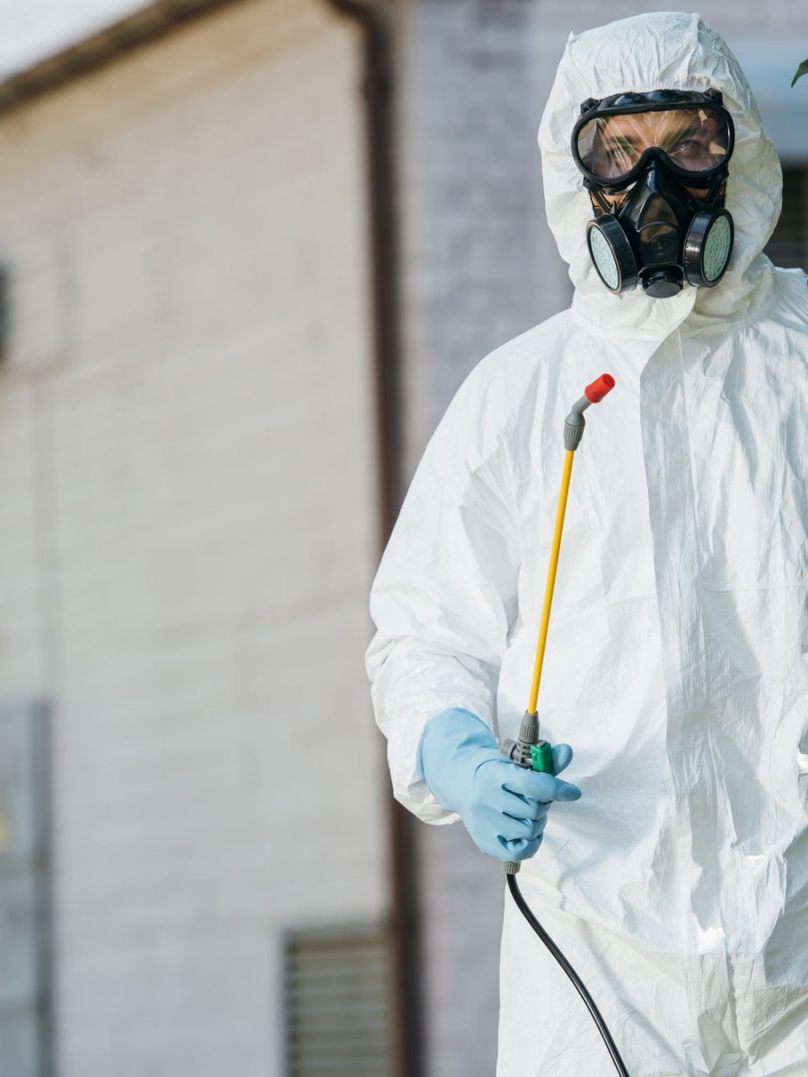 pest control worker in respirator holding sprayer